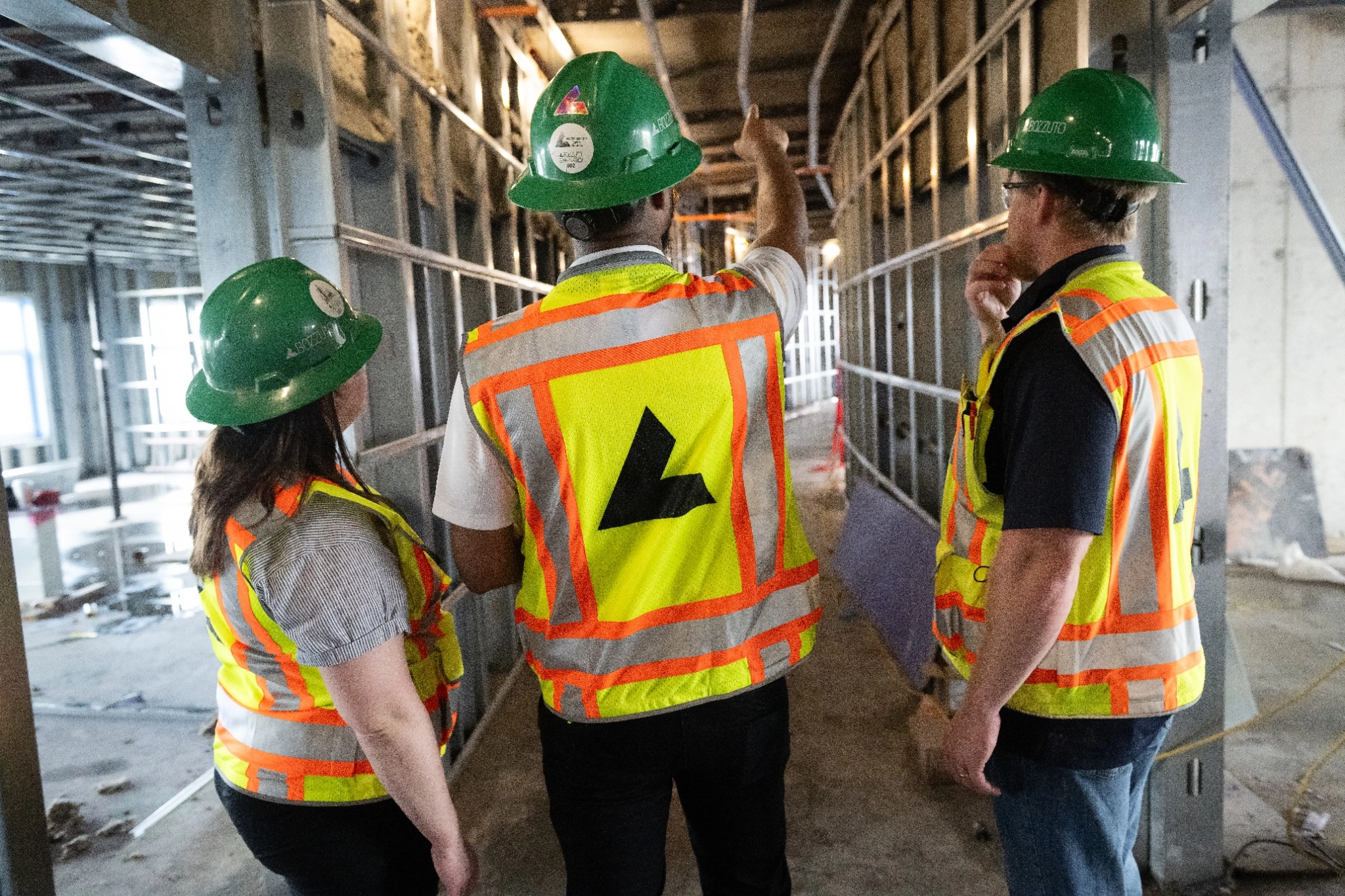 Three construction workers inspecting a building site with safety gear.