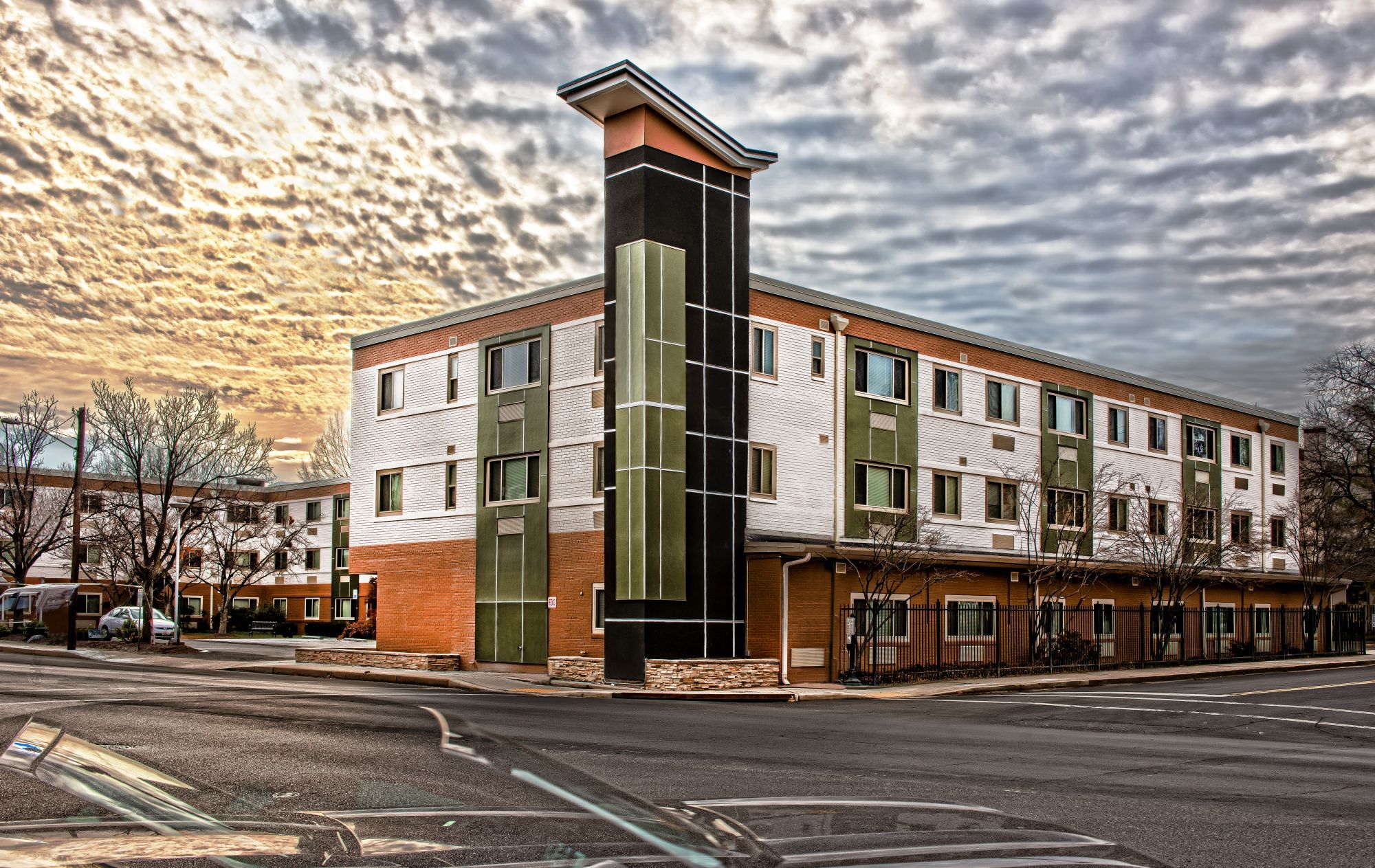 A modern, three-story hotel with a distinctive architectural design against a cloudy sky.