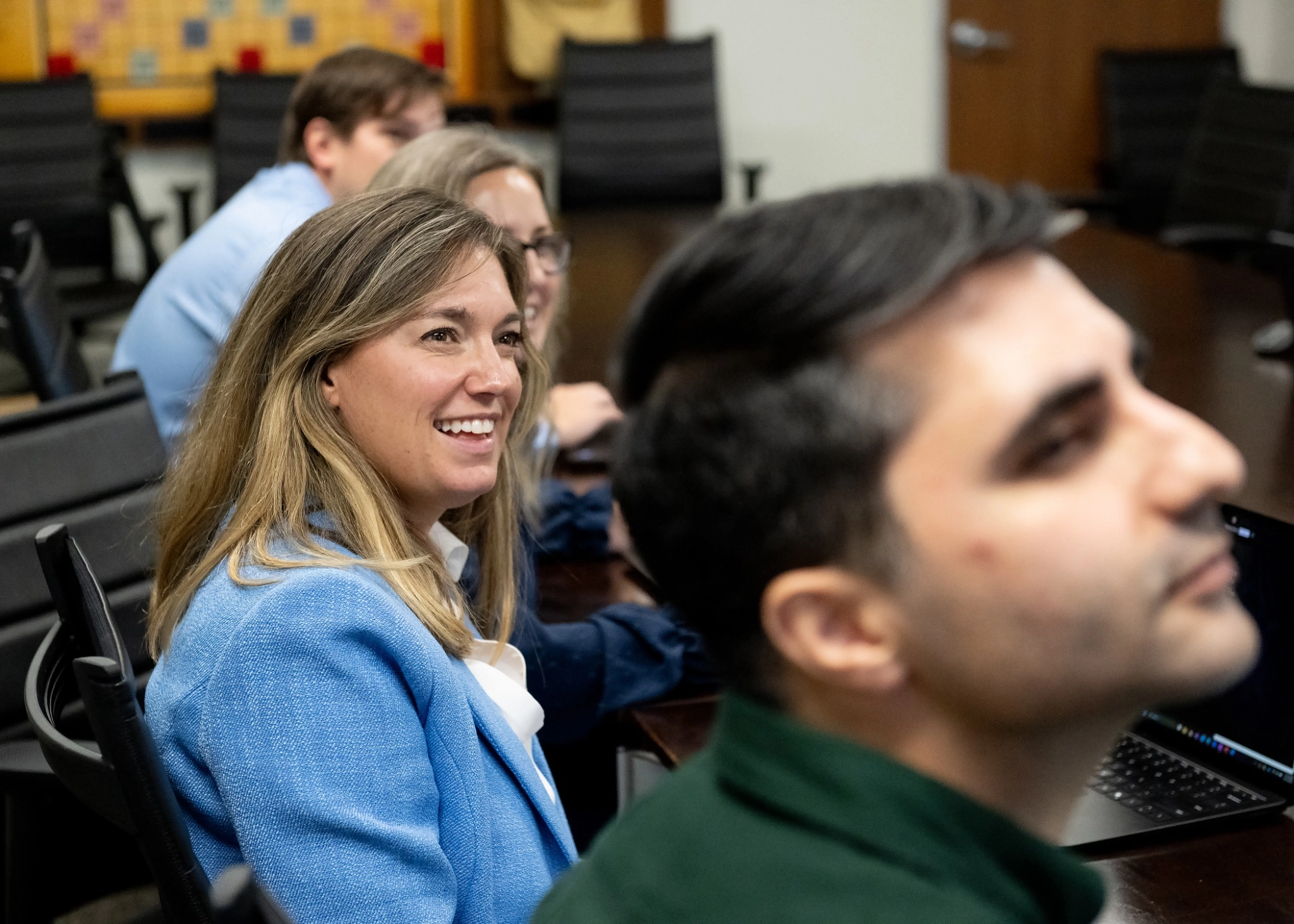 Group of people in a meeting, focused on a woman smiling.