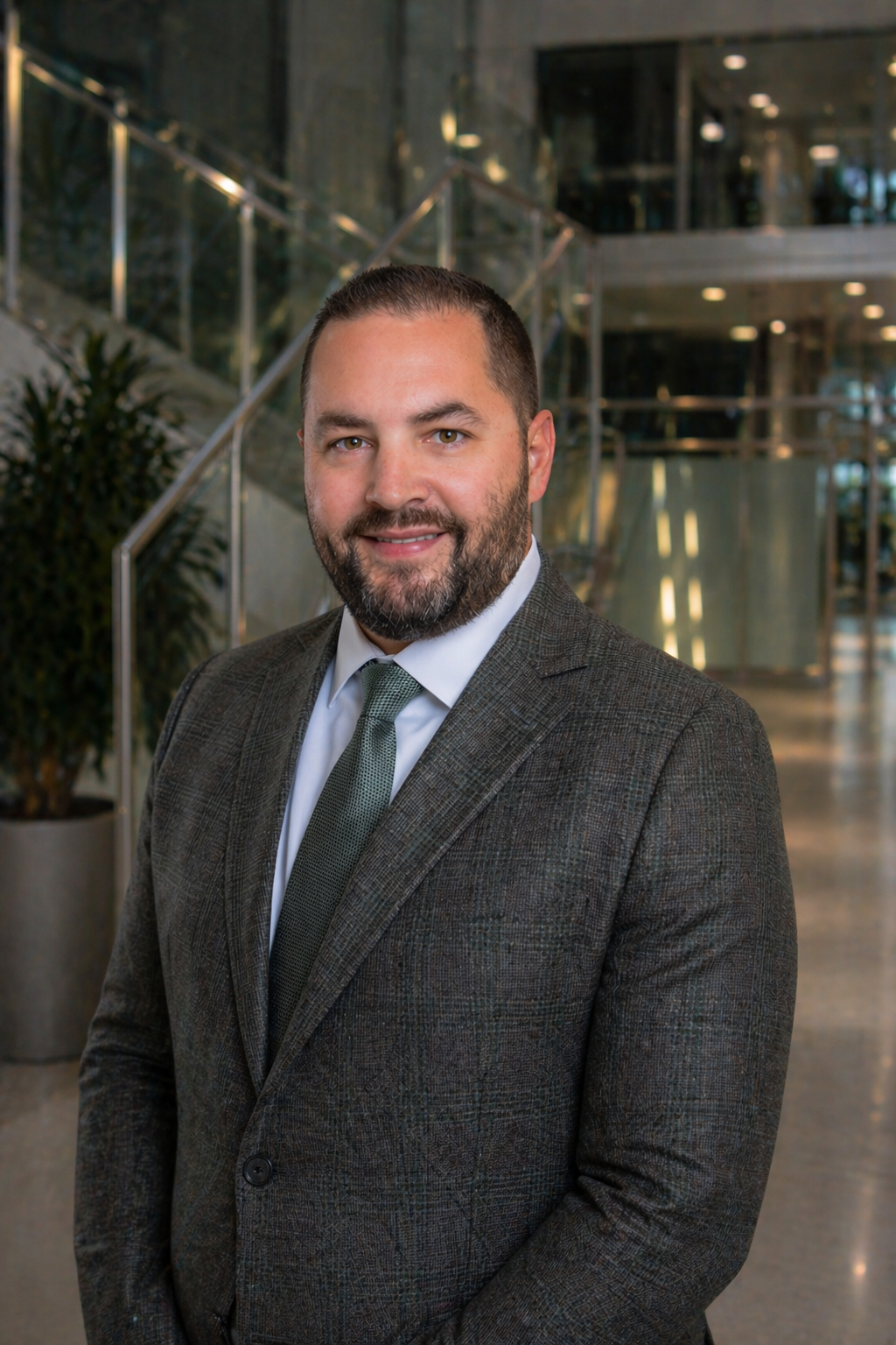 Professional man in a suit stands in a modern office lobby.