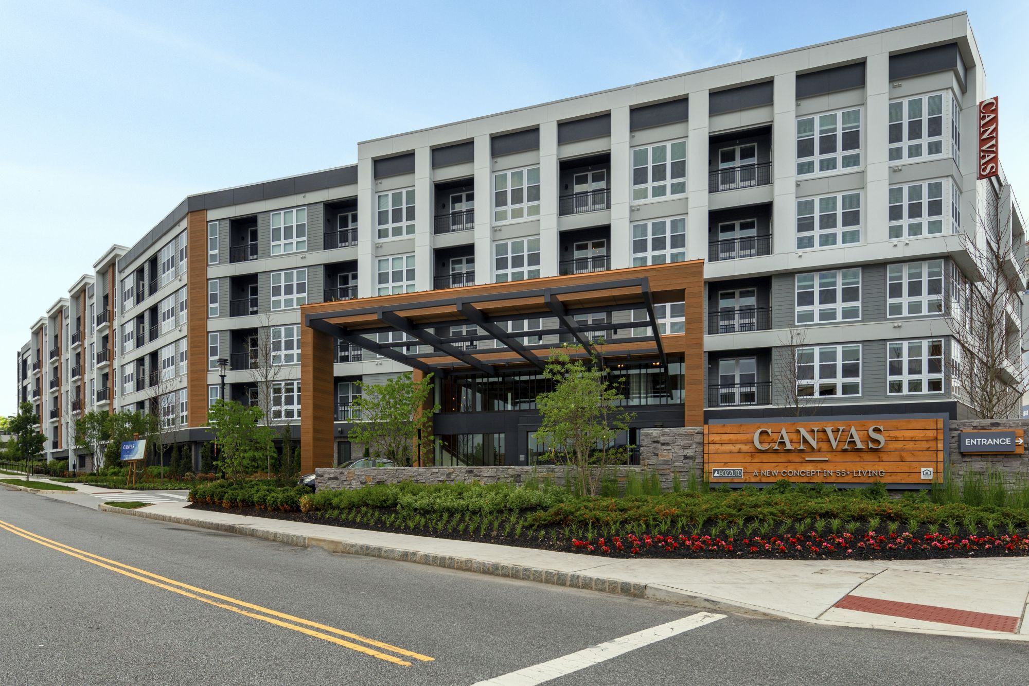 Modern apartment building with a wooden entrance and landscaping.