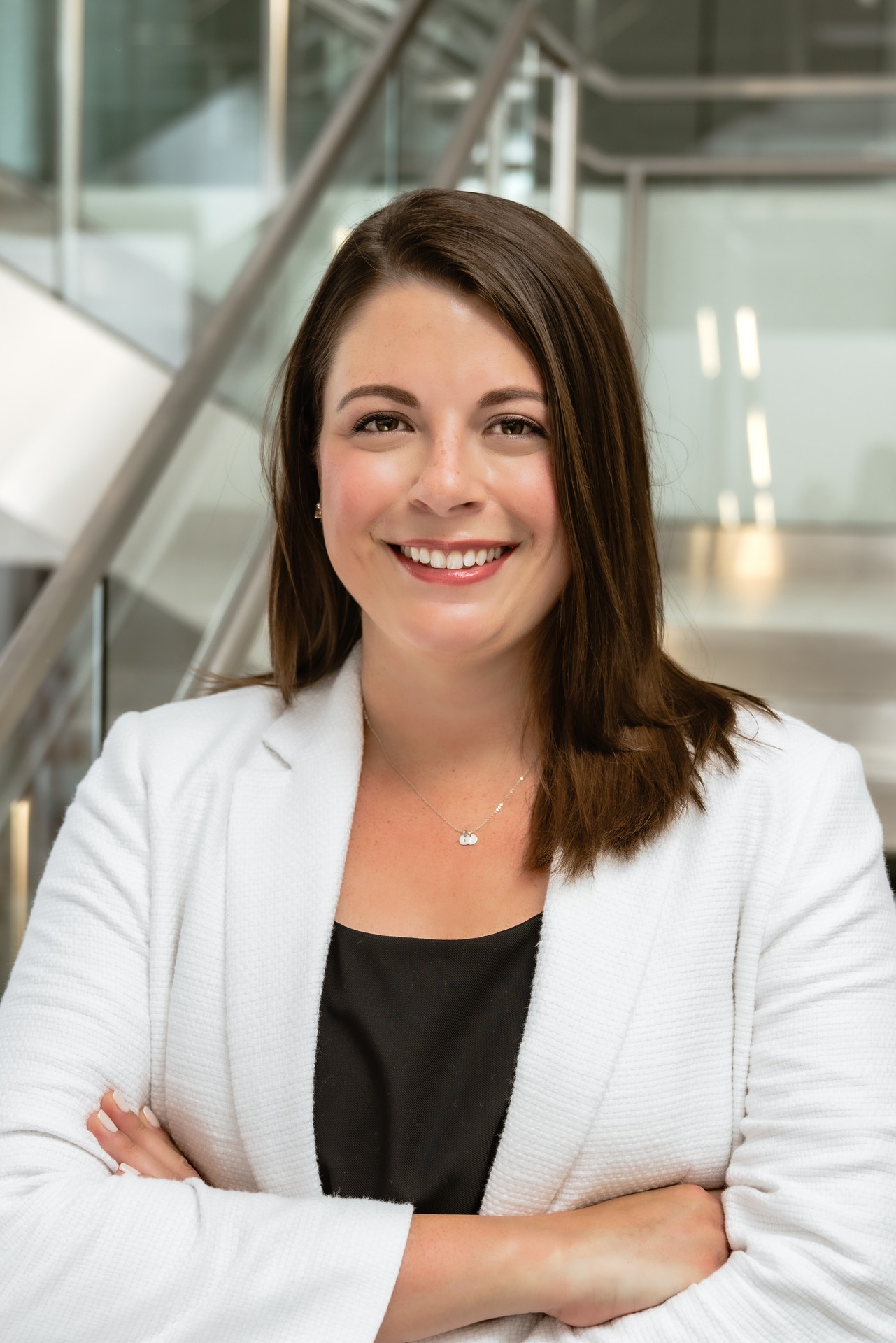 Portrait of Caroline Berry, smiling, wearing a white blazer, with a modern background.