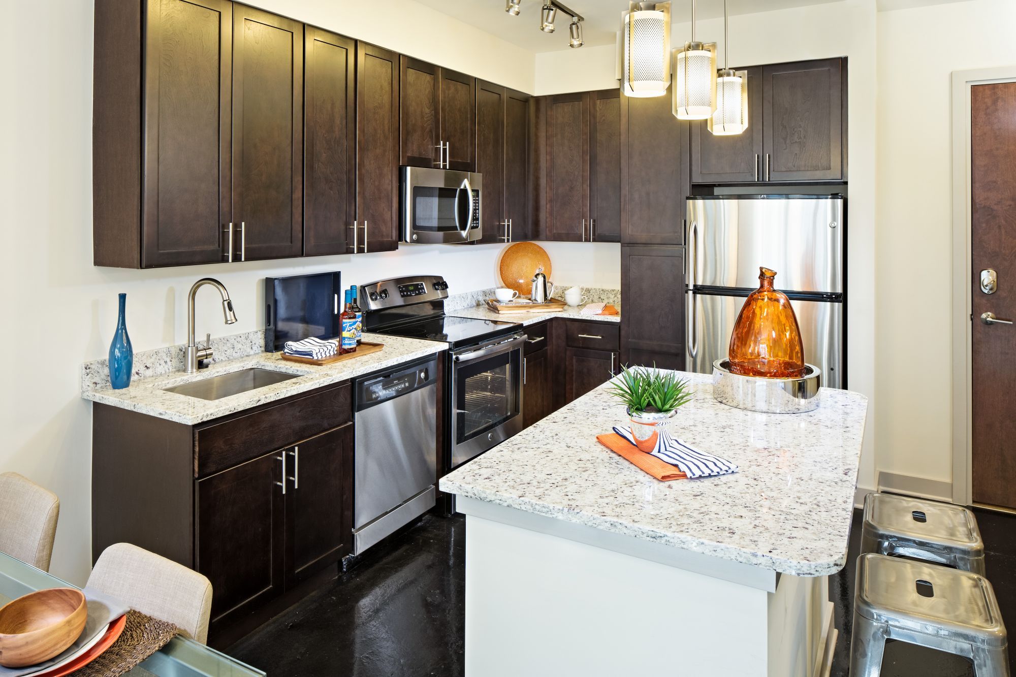 Modern kitchen with dark cabinetry, granite countertops, and stainless steel appliances.
