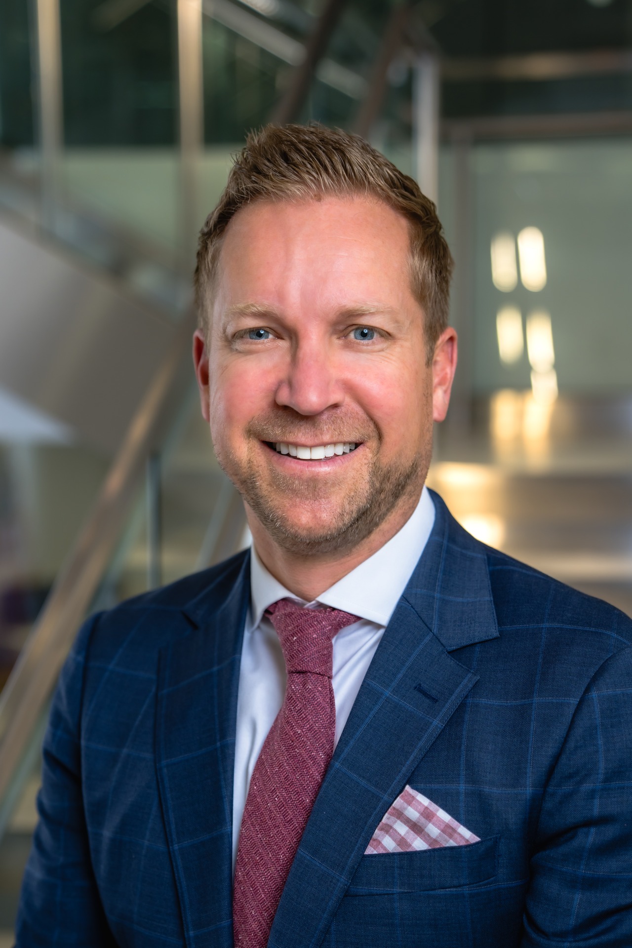 Professional portrait of Edward Okonski III, smiling in a business suit with a modern background.