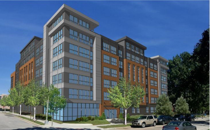 Modern multi-story building with large windows and greenery outside.