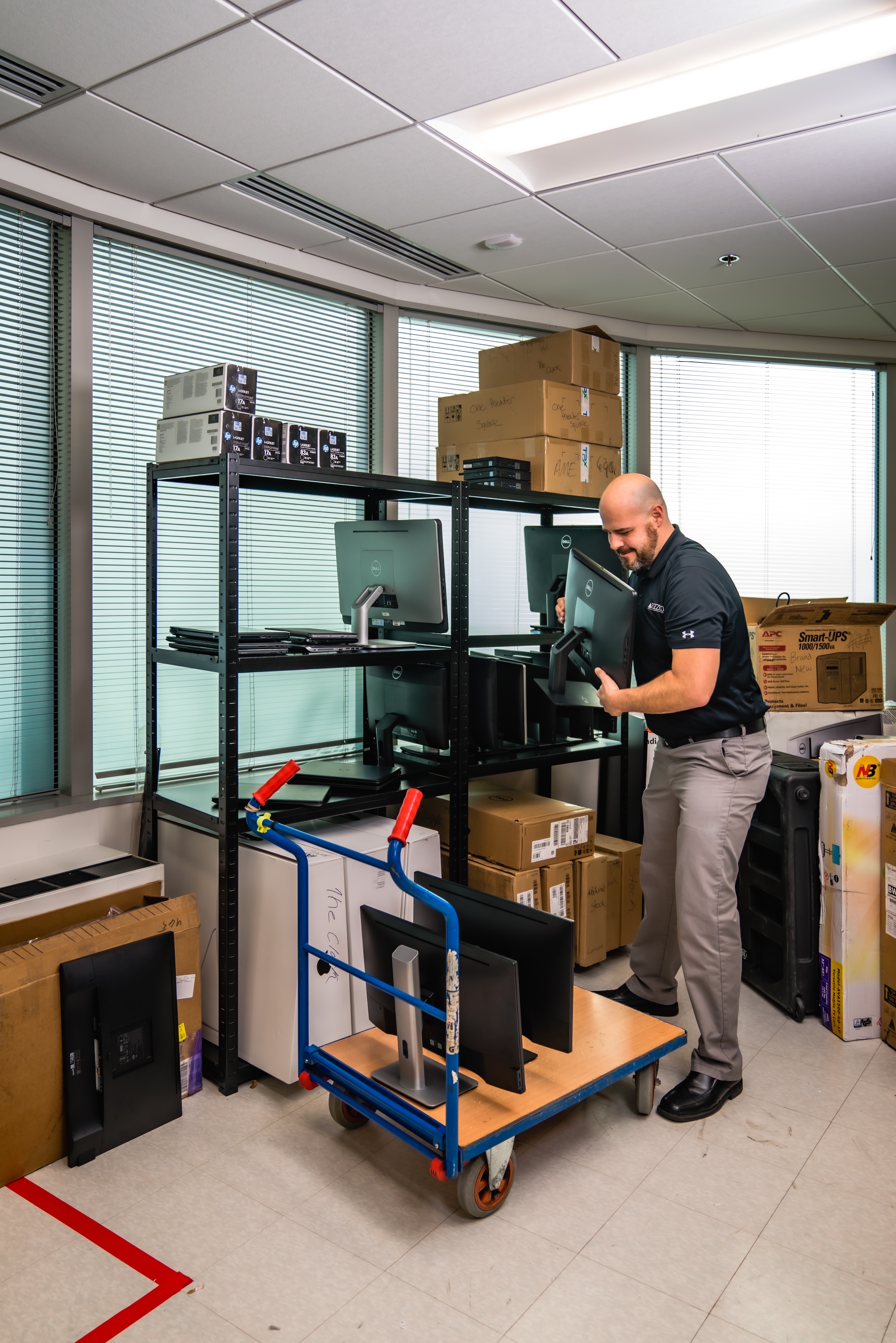 A person organizing equipment on a shelf in an office space.