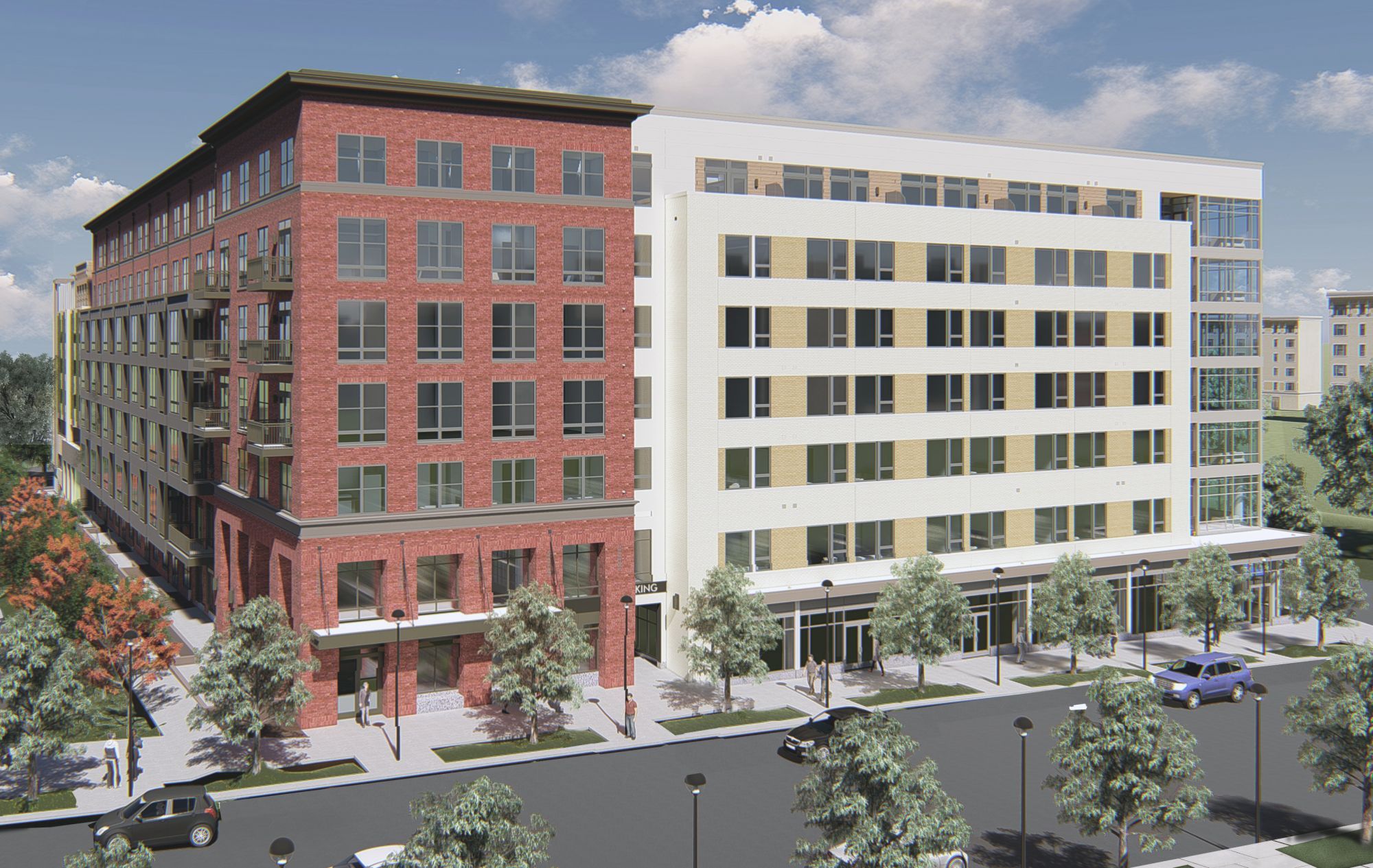 Modern mixed-use building with brick and glass facade, surrounded by trees and parking.