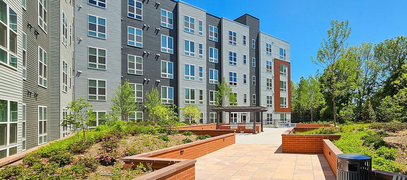 Modern apartment building with landscaped entrance and clear blue sky.