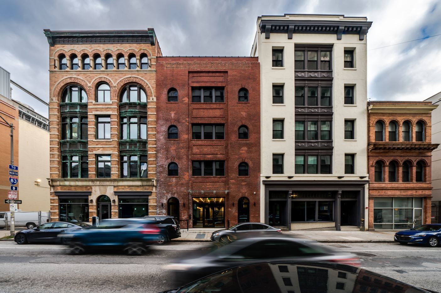 Three distinct buildings with varying architectural styles and a cloudy sky above.