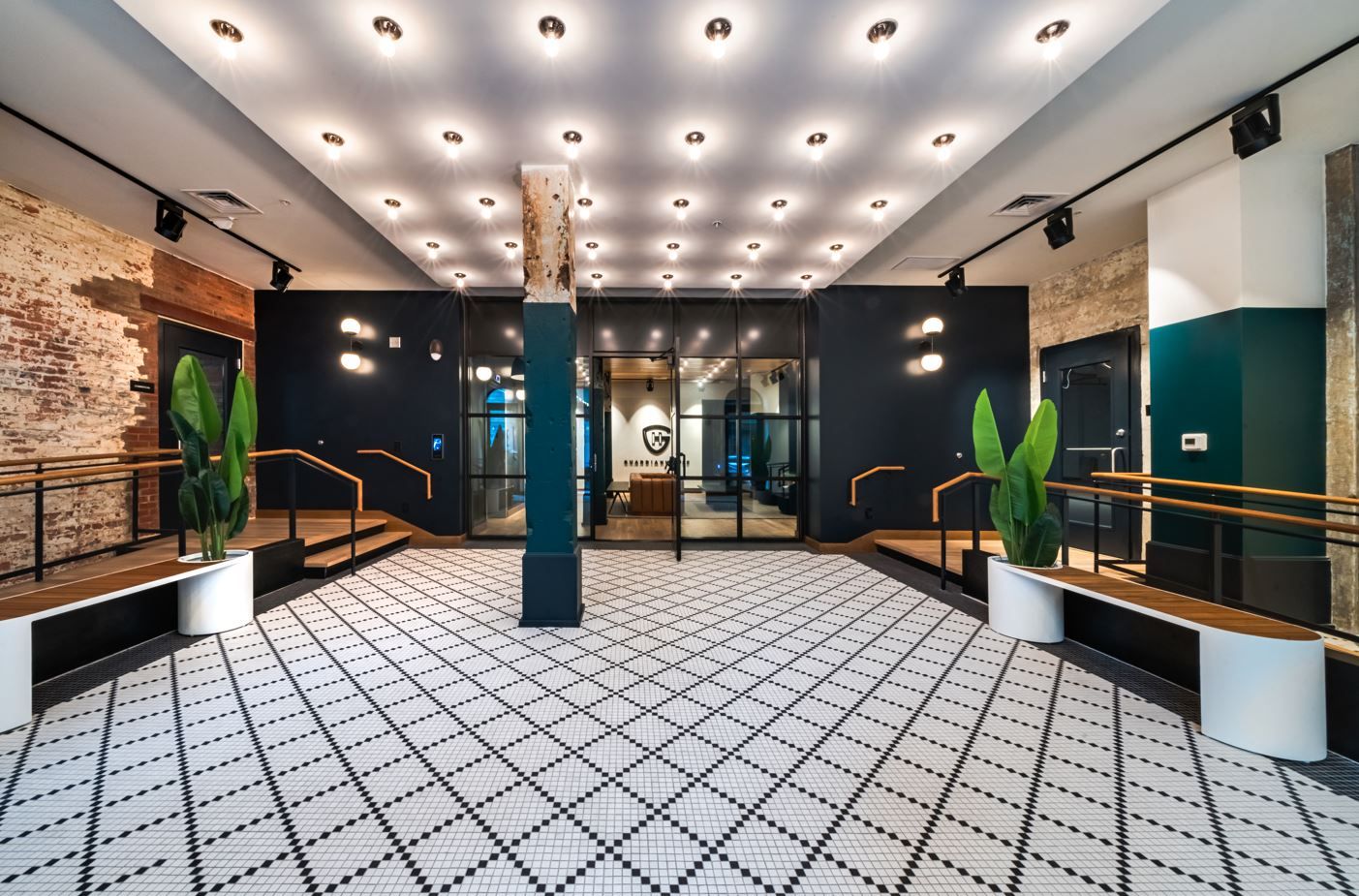 Modern interior with checkered floor, plants, and a dark focal wall with glass doors.