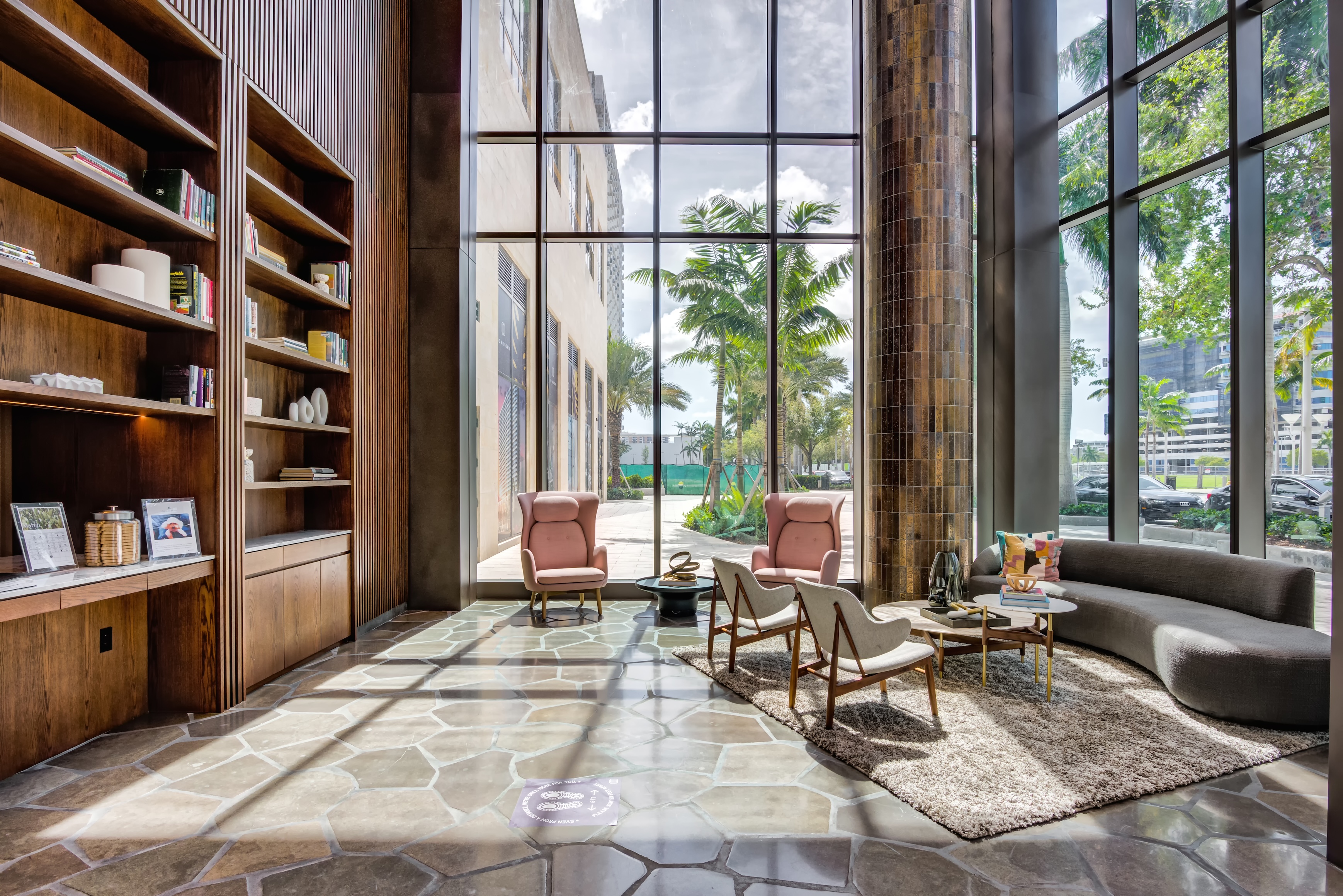 Modern lobby with large windows, wood accents, and stylish furniture.