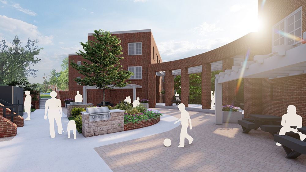 A sunlit courtyard with people, benches, and greenery in a modern setting.