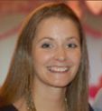 Smiling woman with long brown hair in a blurred background.