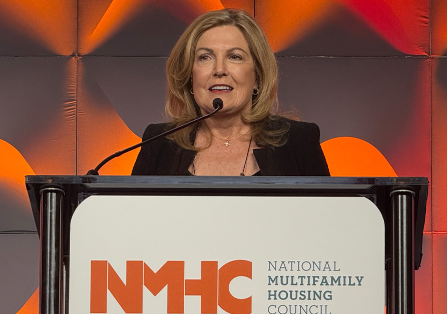 A woman speaks at a podium with the NMHC logo in the background.
