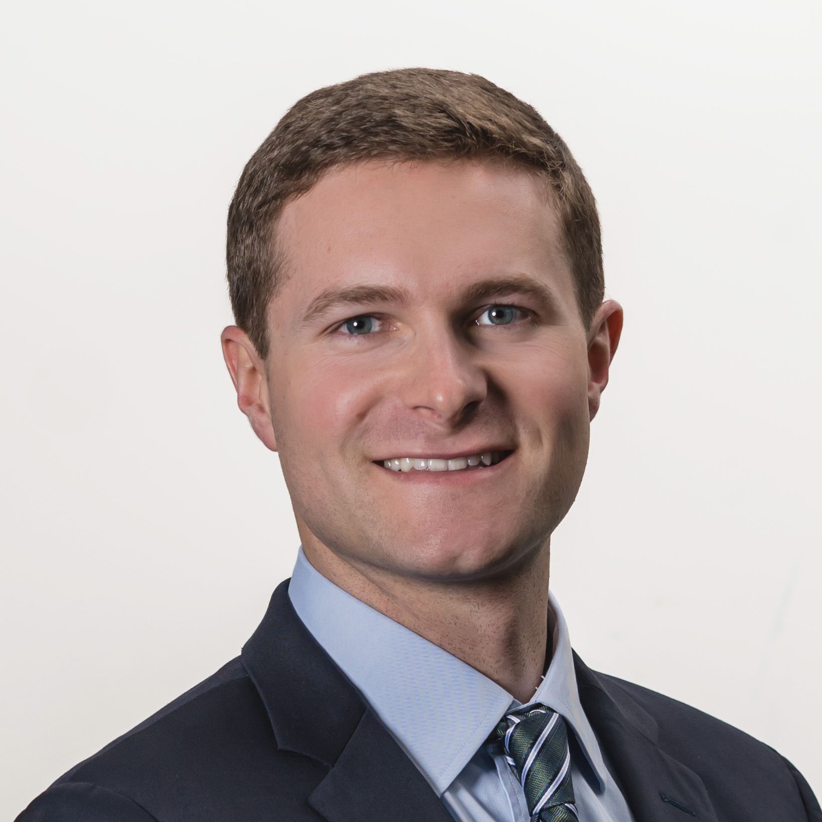 Smiling man in a suit against a plain white background.