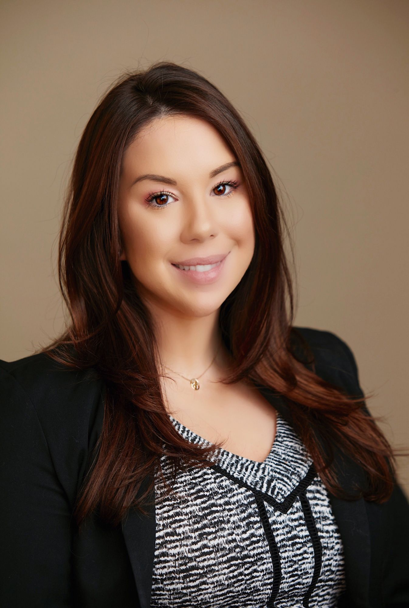 Professional portrait of a woman with long dark hair, smiling against a neutral background.