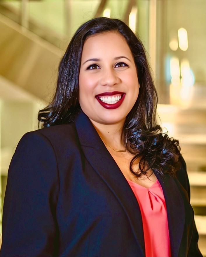 Jessica Gonzalez smiles confidently in a professional setting with a modern background.