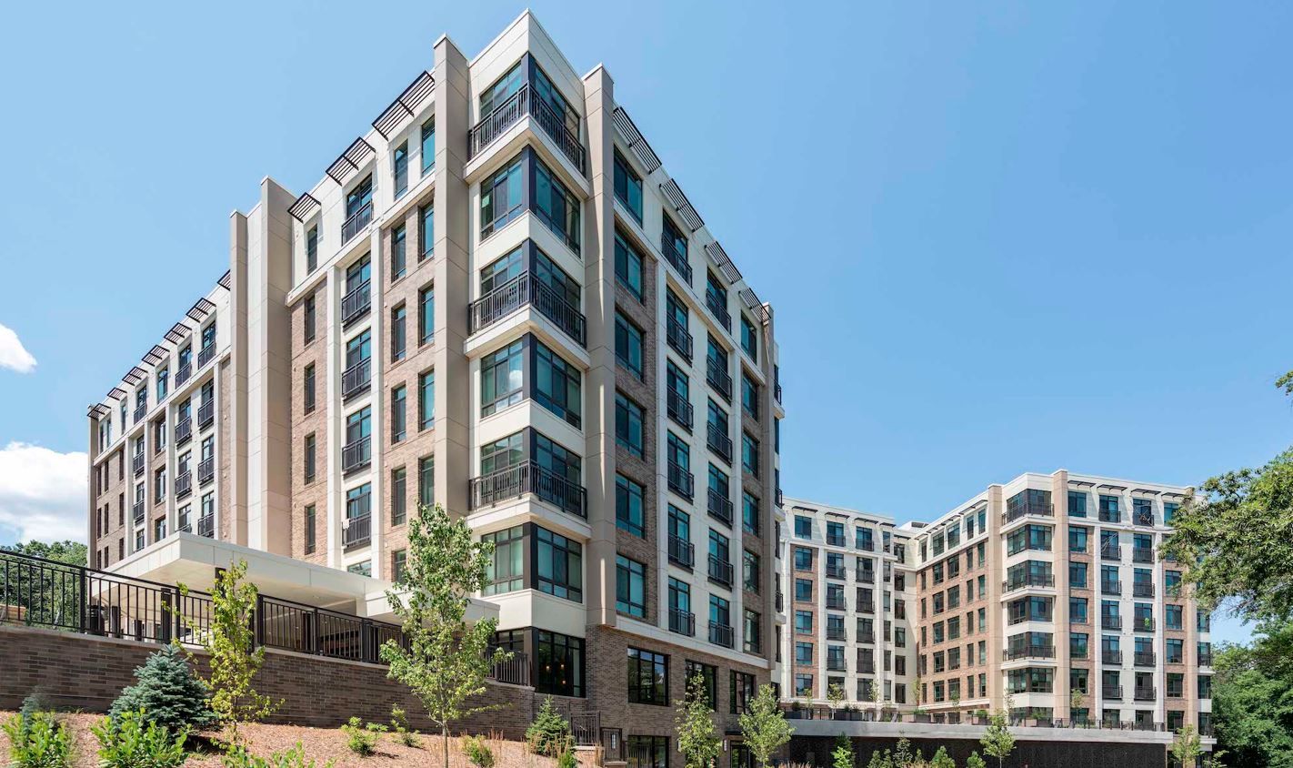 Modern multi-story building with large windows and landscaped surroundings.