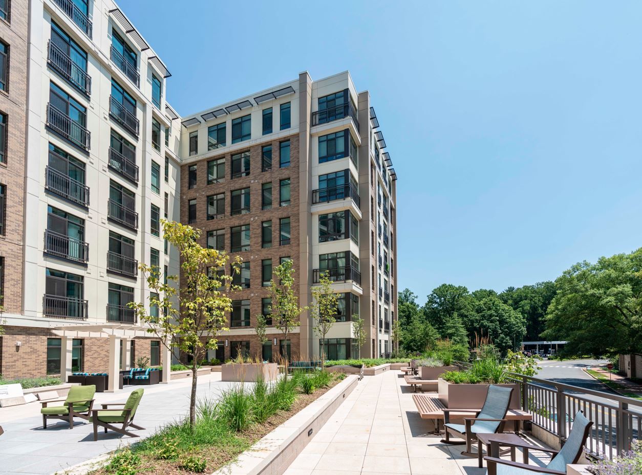 Modern apartment building with a landscaped patio and lounge seating.