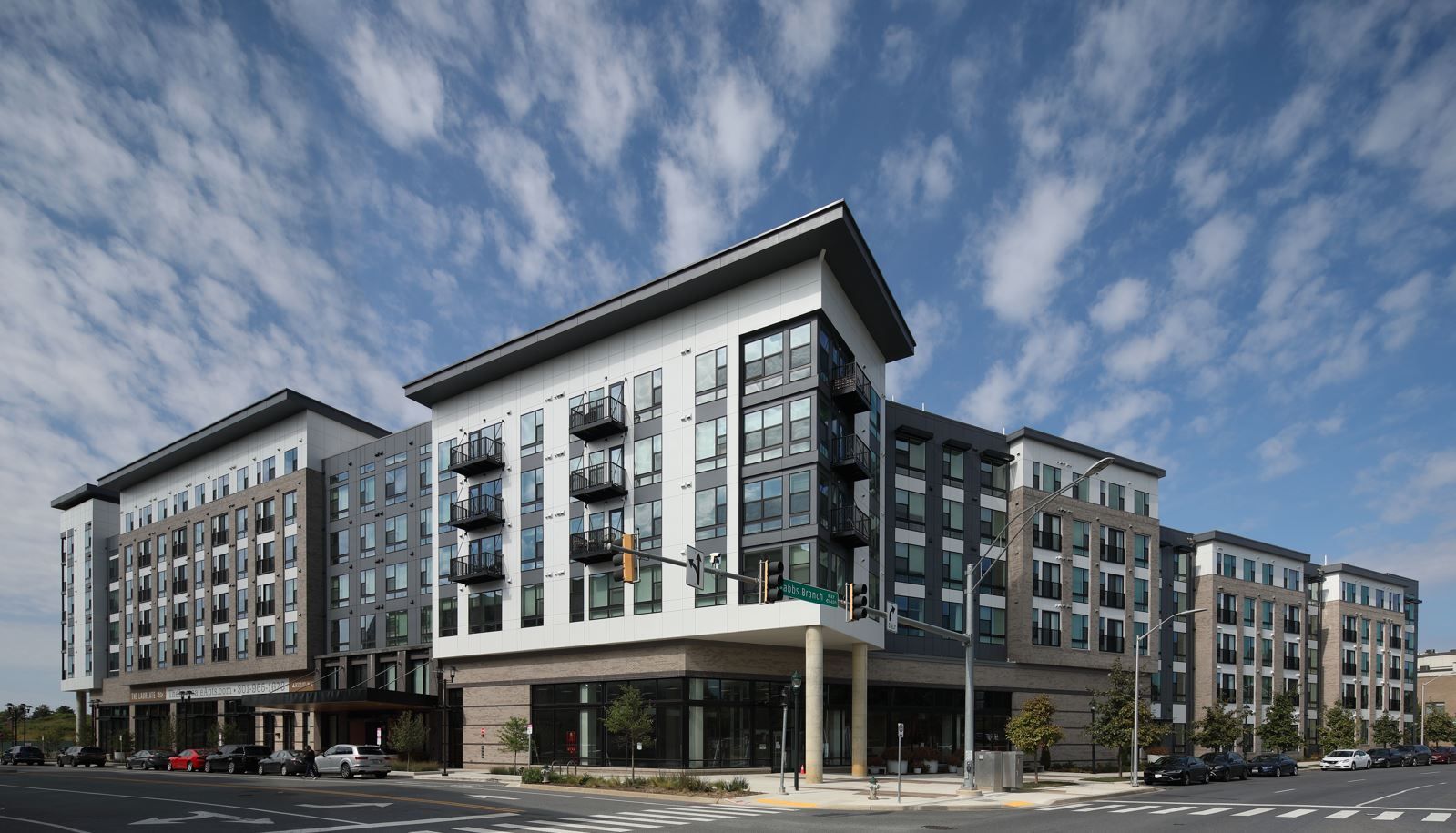 Modern apartment building with large windows and balconies under a partly cloudy sky.