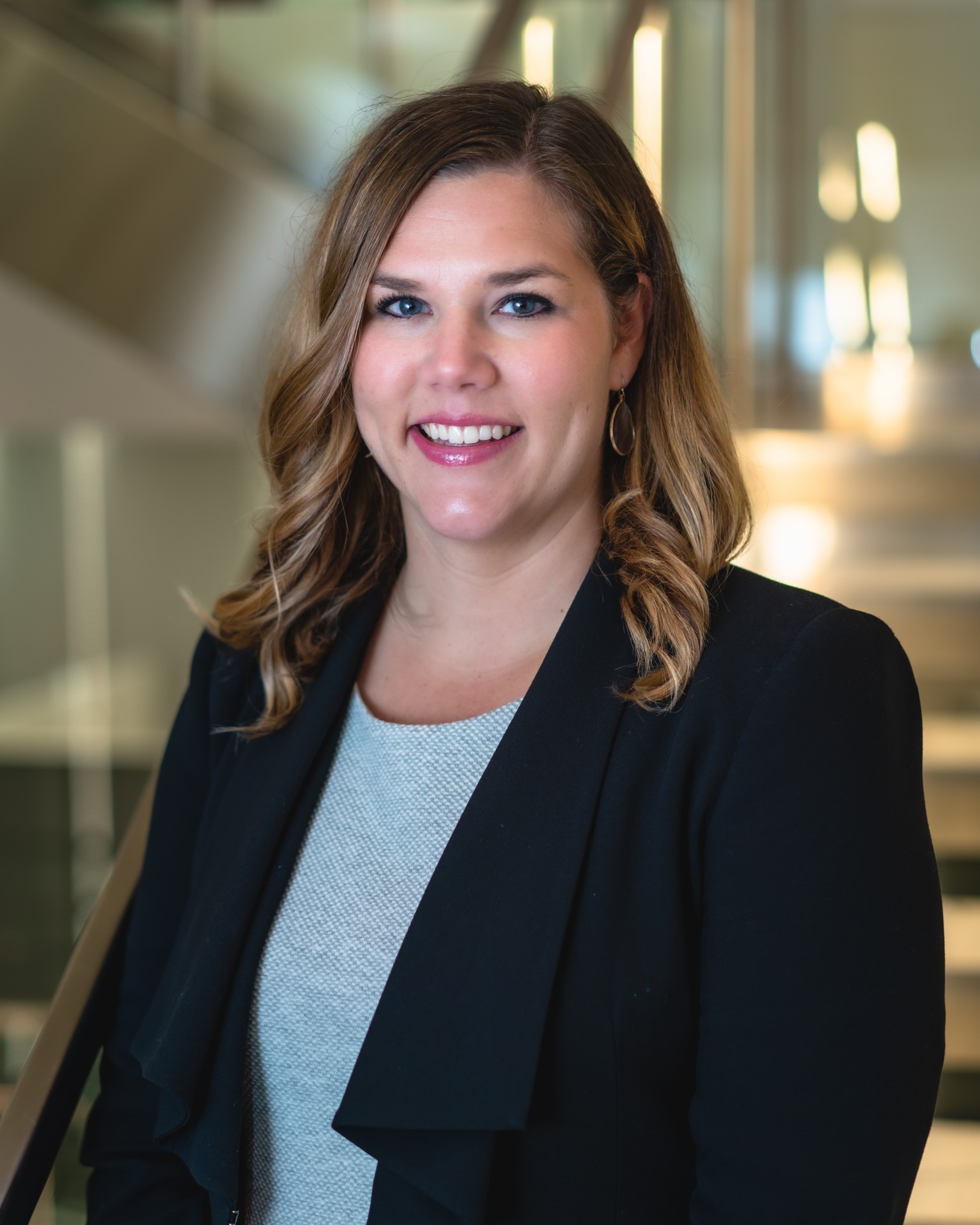 Portrait of Lauren Jarboe smiling, dressed in a blazer, with a modern office background.