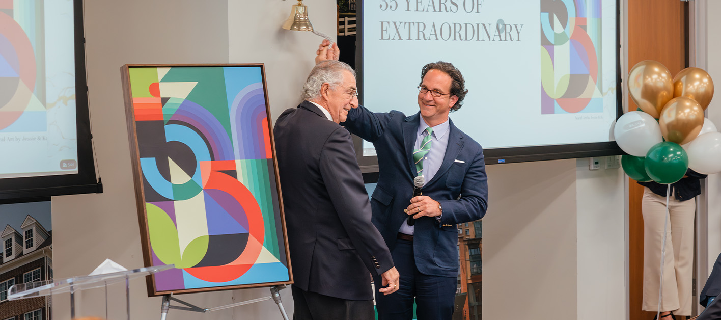 Two men at an event unveiling an artwork with colorful design.