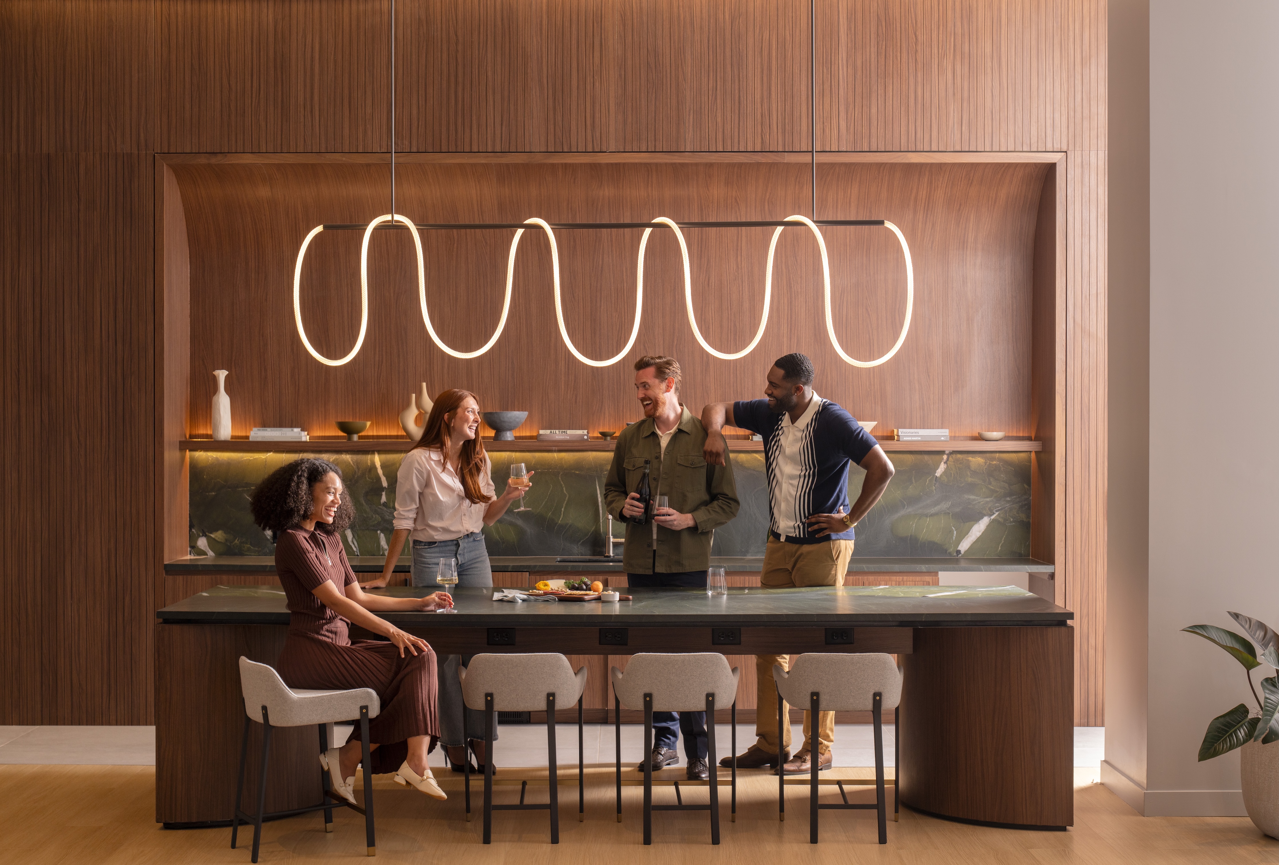Four people chatting around a modern kitchen island with warm lighting.