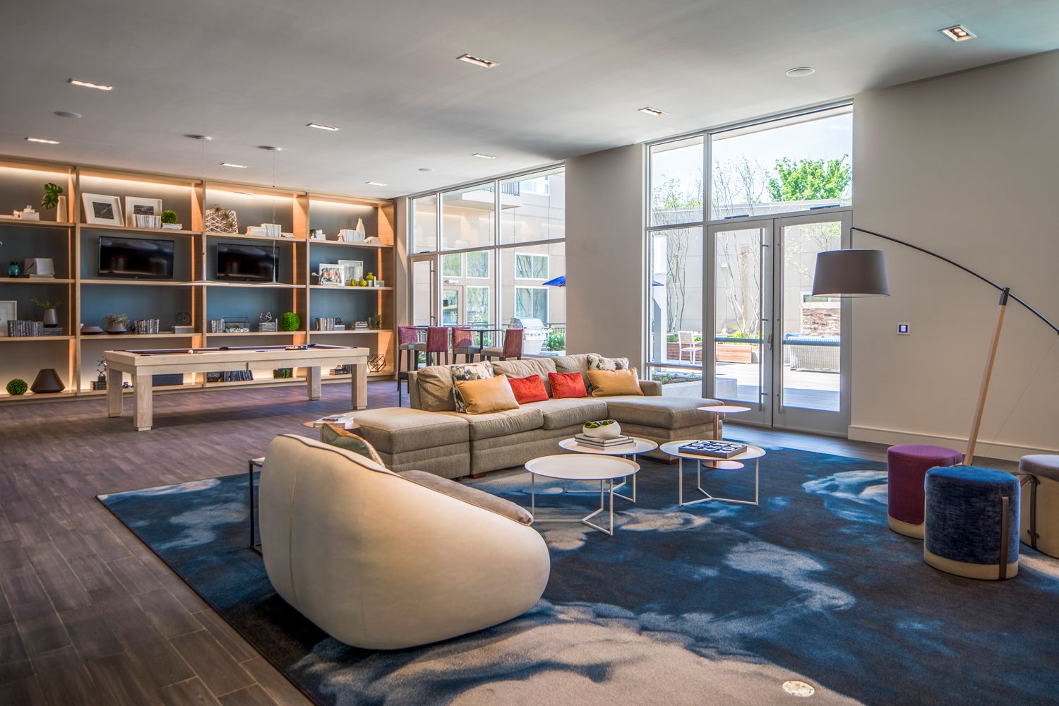 Stylish modern living room with a sectional sofa, coffee tables, and large windows.