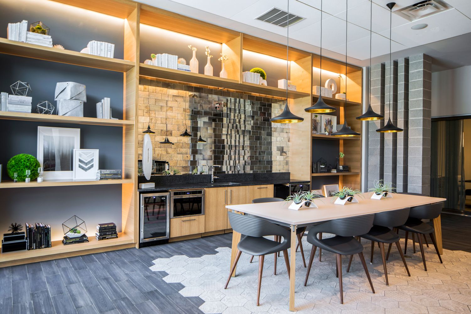 Modern kitchen and dining area with wooden shelves, a large table, and stylish lighting.