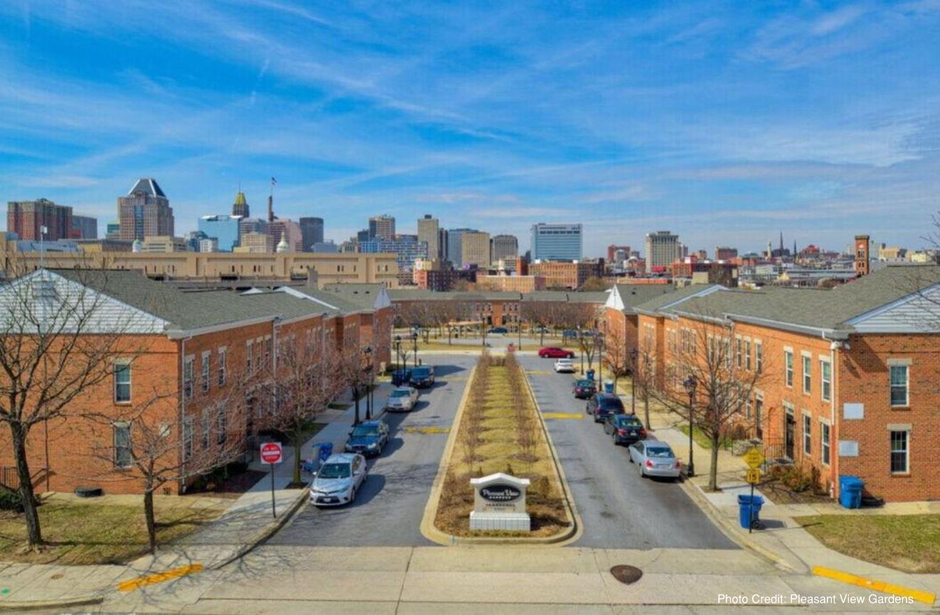 Residential community with rows of two-story brick apartment buildings lining a landscaped boulevard.