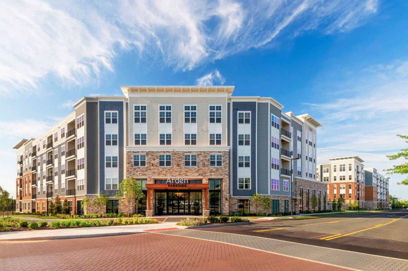 Modern apartment building with a blue sky and paved entrance.