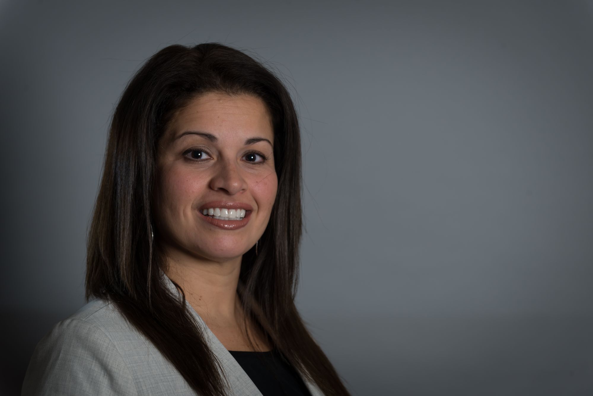 A woman smiling against a neutral background.