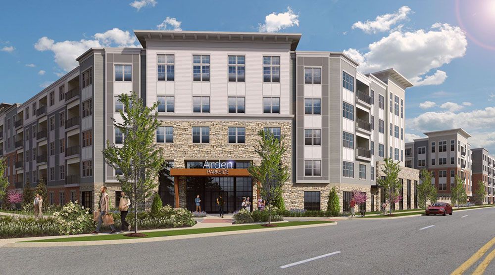 Modern multi-story apartment building with greenery and blue skies.