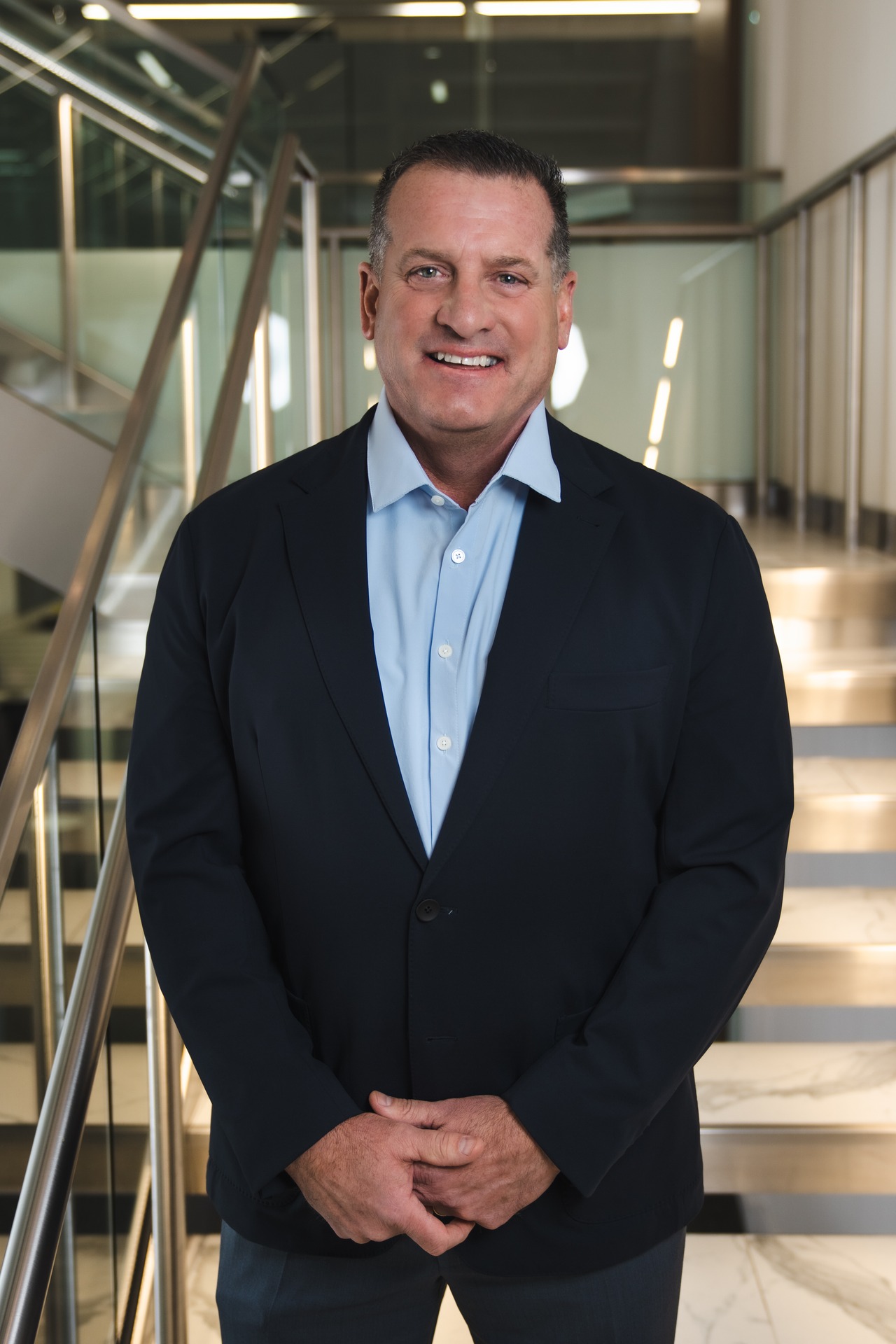 Robert Loscalzo stands smiling on a staircase, wearing a dark blazer over a light shirt.