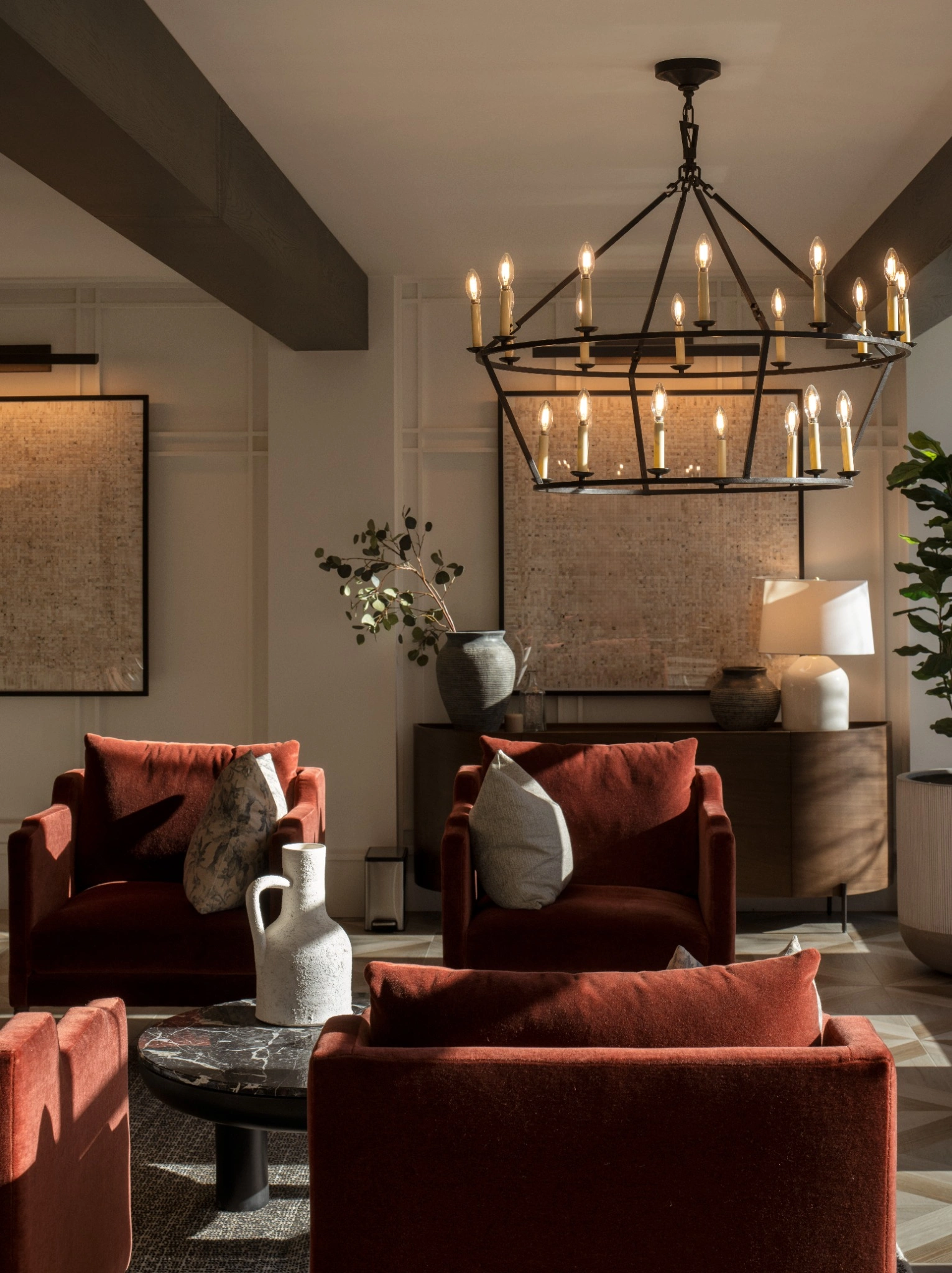 Cozy living room with orange chairs and a large chandelier.