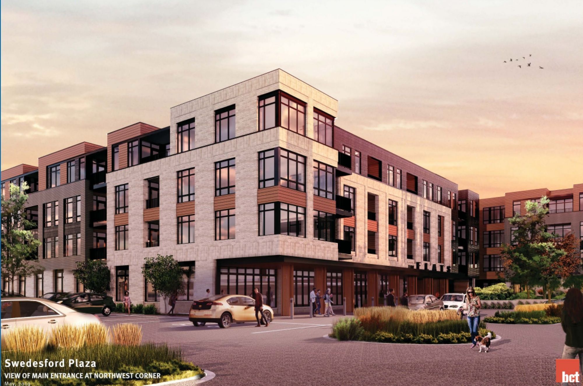 Modern multi-story building with large windows and landscaped surroundings at sunset.