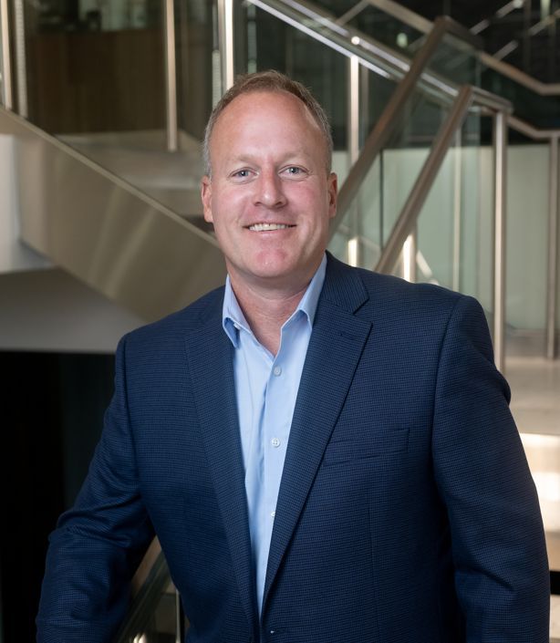 Smiling man in a suit standing in a modern office space.