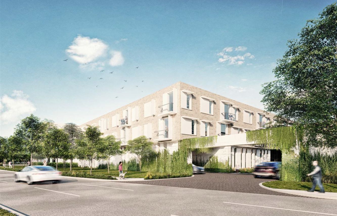 Modern building with greenery and cars, under a clear blue sky.