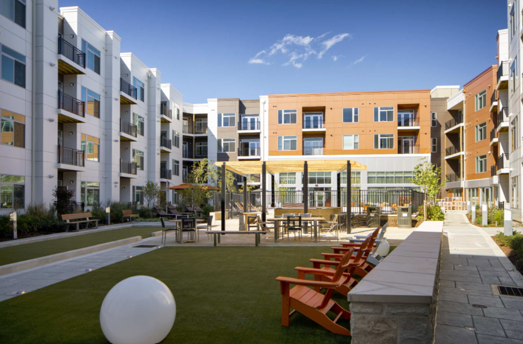 Modern apartment community courtyard surrounded by multi-story residential buildings with balconies and large windows.