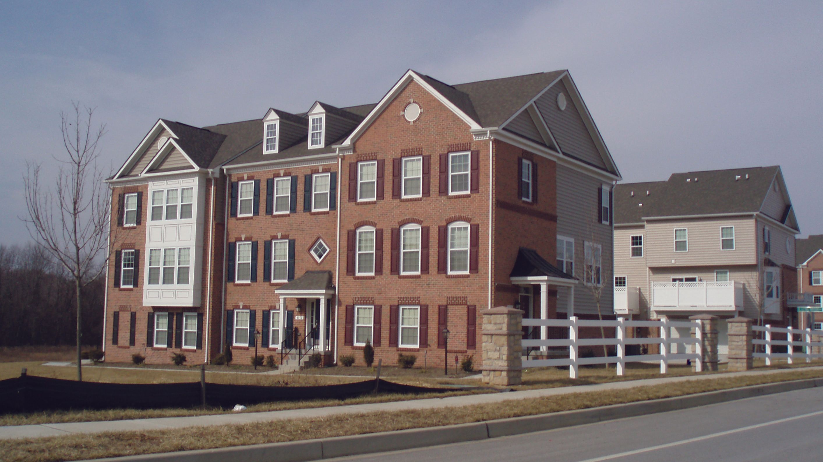 Brick townhouse with multiple stories and a landscaped front yard.