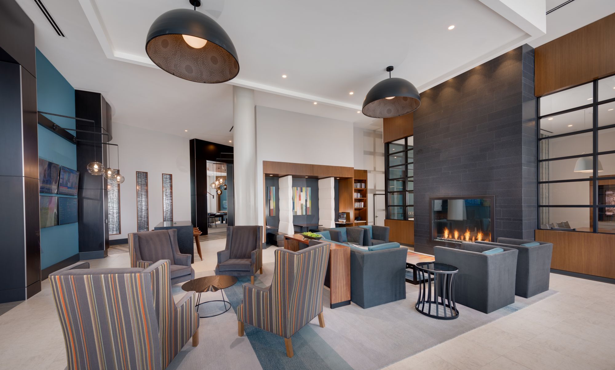 Modern lobby with seating, pendant lights, and a fireplace.