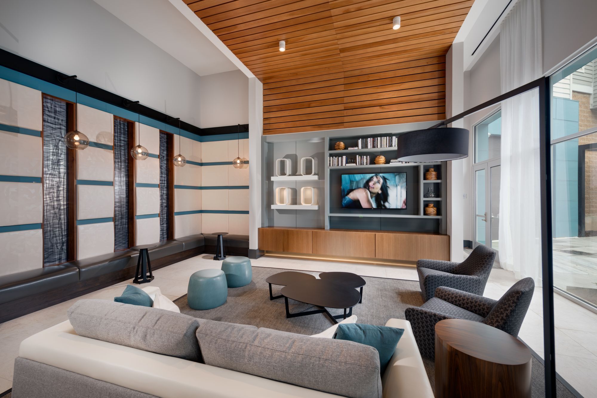 Modern living room with a wooden ceiling, sleek furniture, and a large TV.