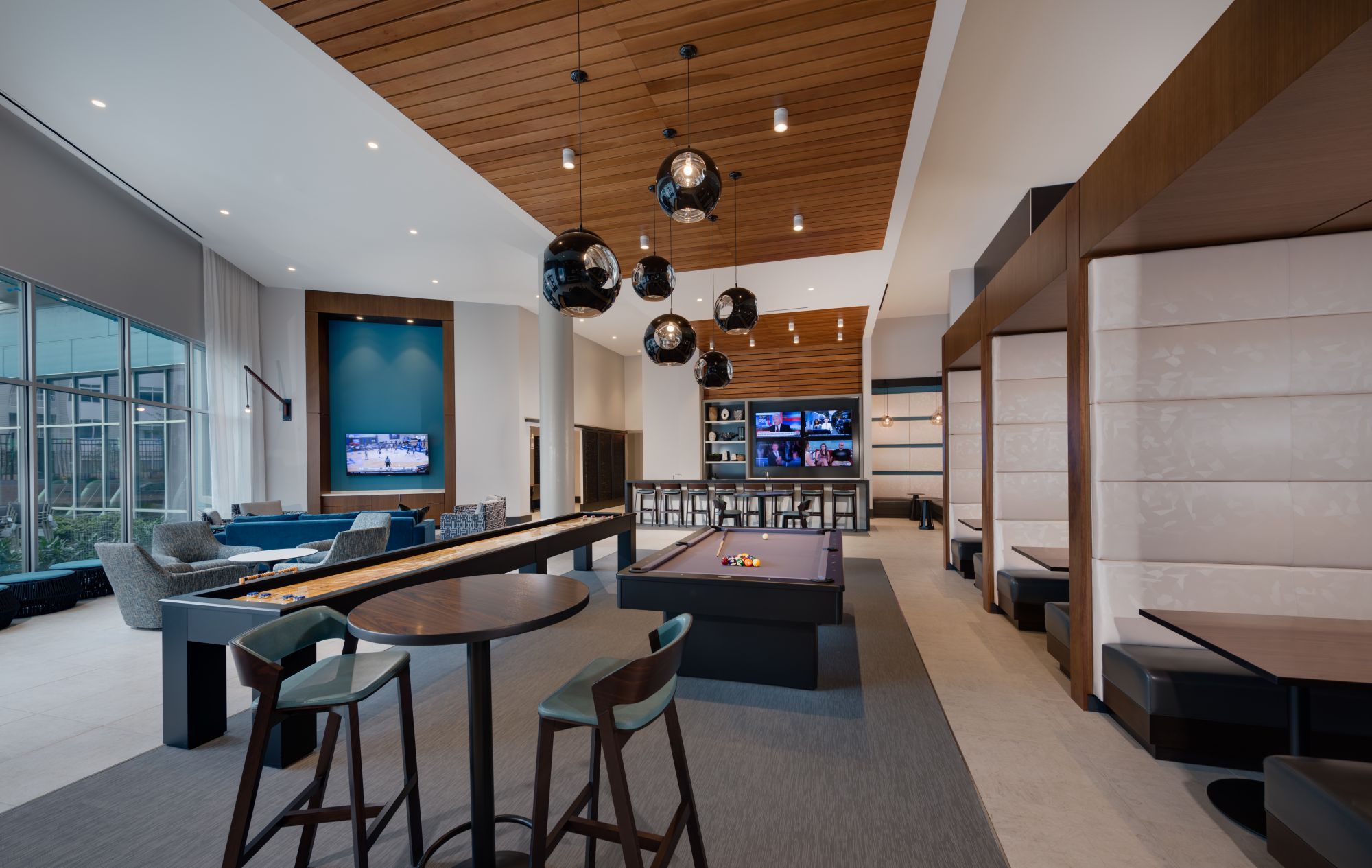Modern lounge with a pool table, bar area, and stylish lighting fixtures.