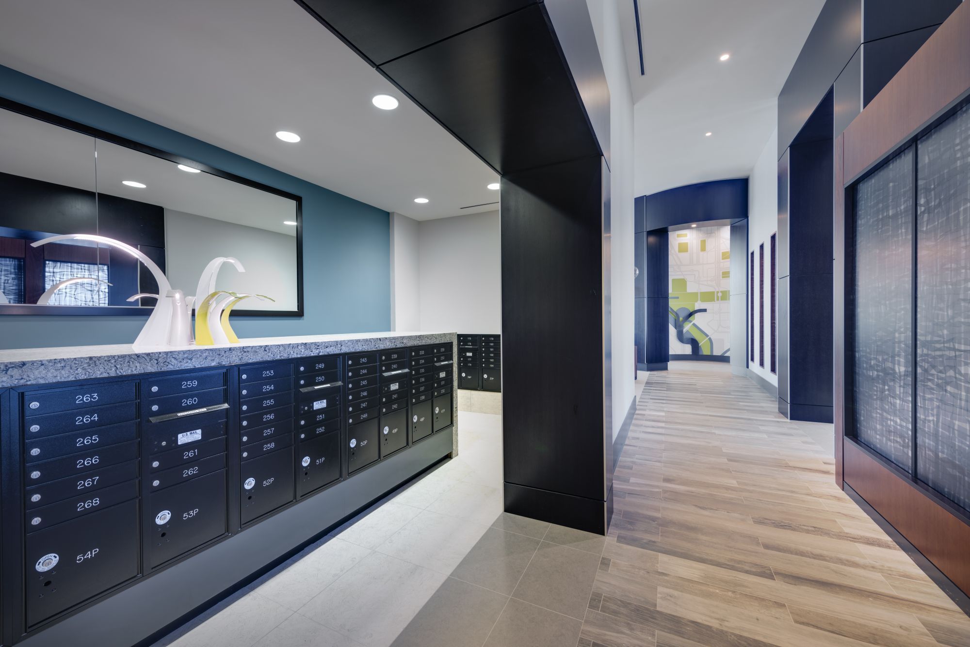 Modern hallway with mailboxes and wooden flooring, featuring sleek lighting and decor.