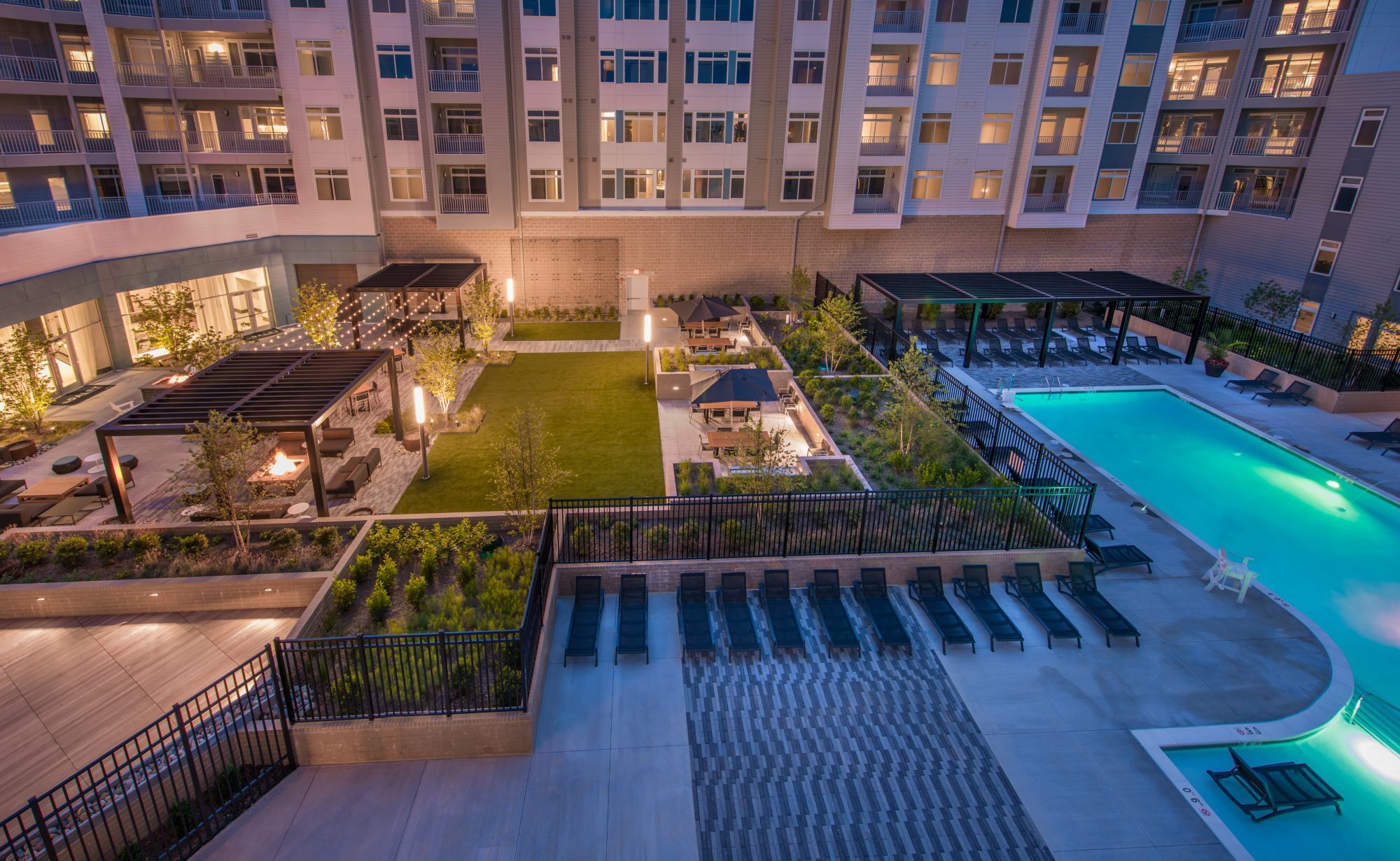Aerial view of a modern apartment complex with a pool and landscaped courtyard.