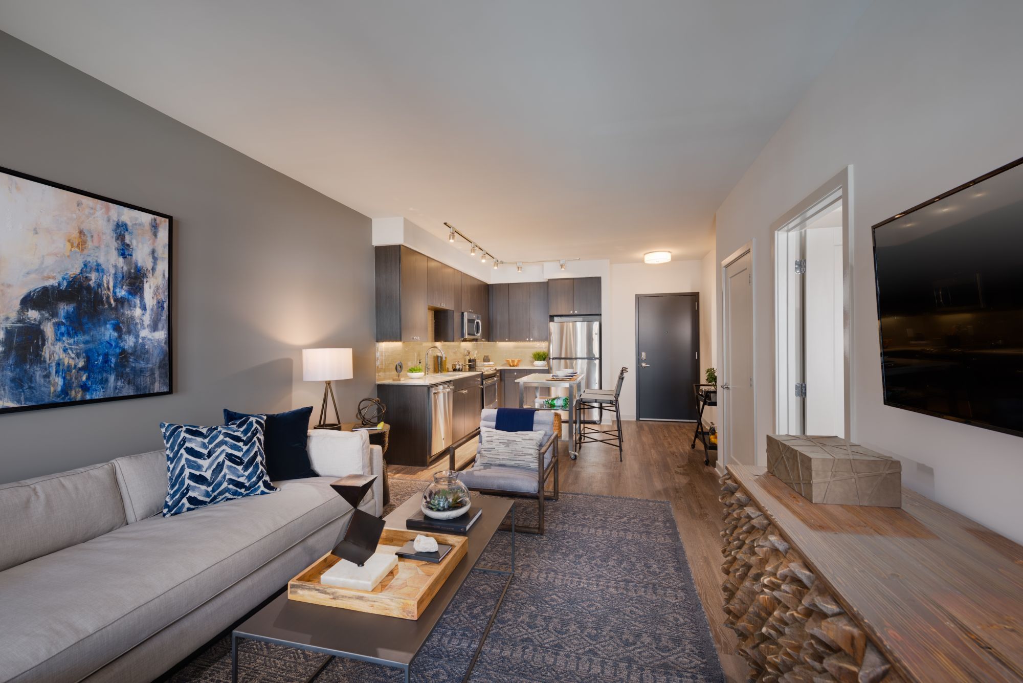 Modern living room with a sofa, coffee table, artwork, and a TV in a stylish, light space.