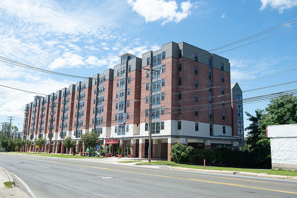 Modern brick apartment building with multiple stories alongside a street.
