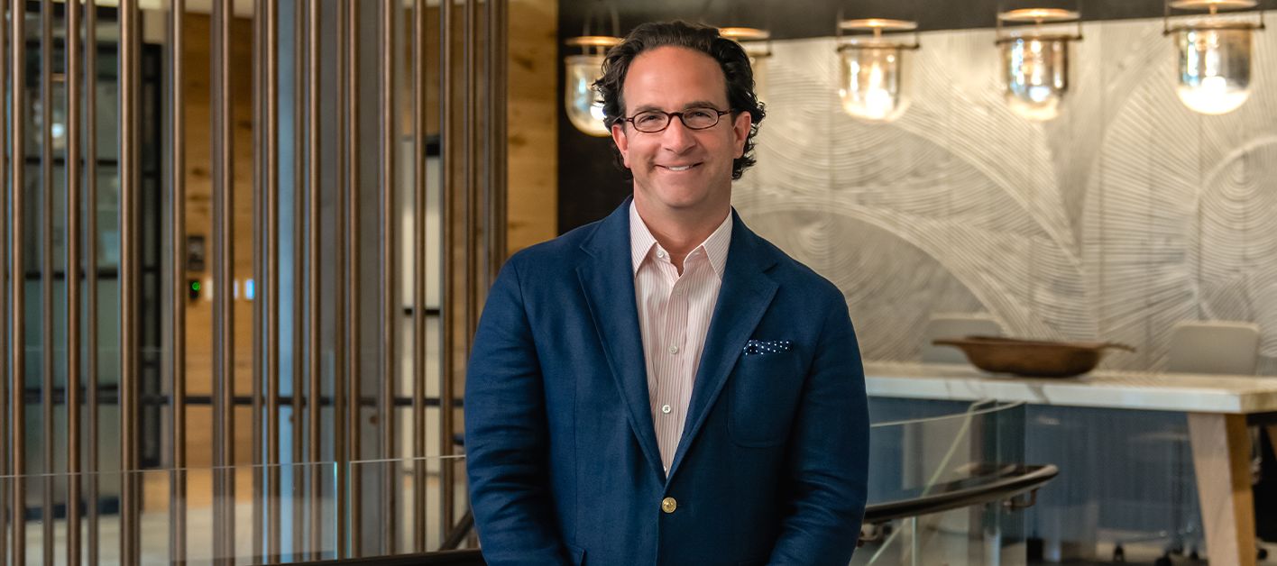 Man in a blue blazer standing in a modern interior space.