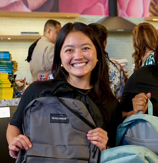 Smiling woman holding a backpack in a vibrant setting.