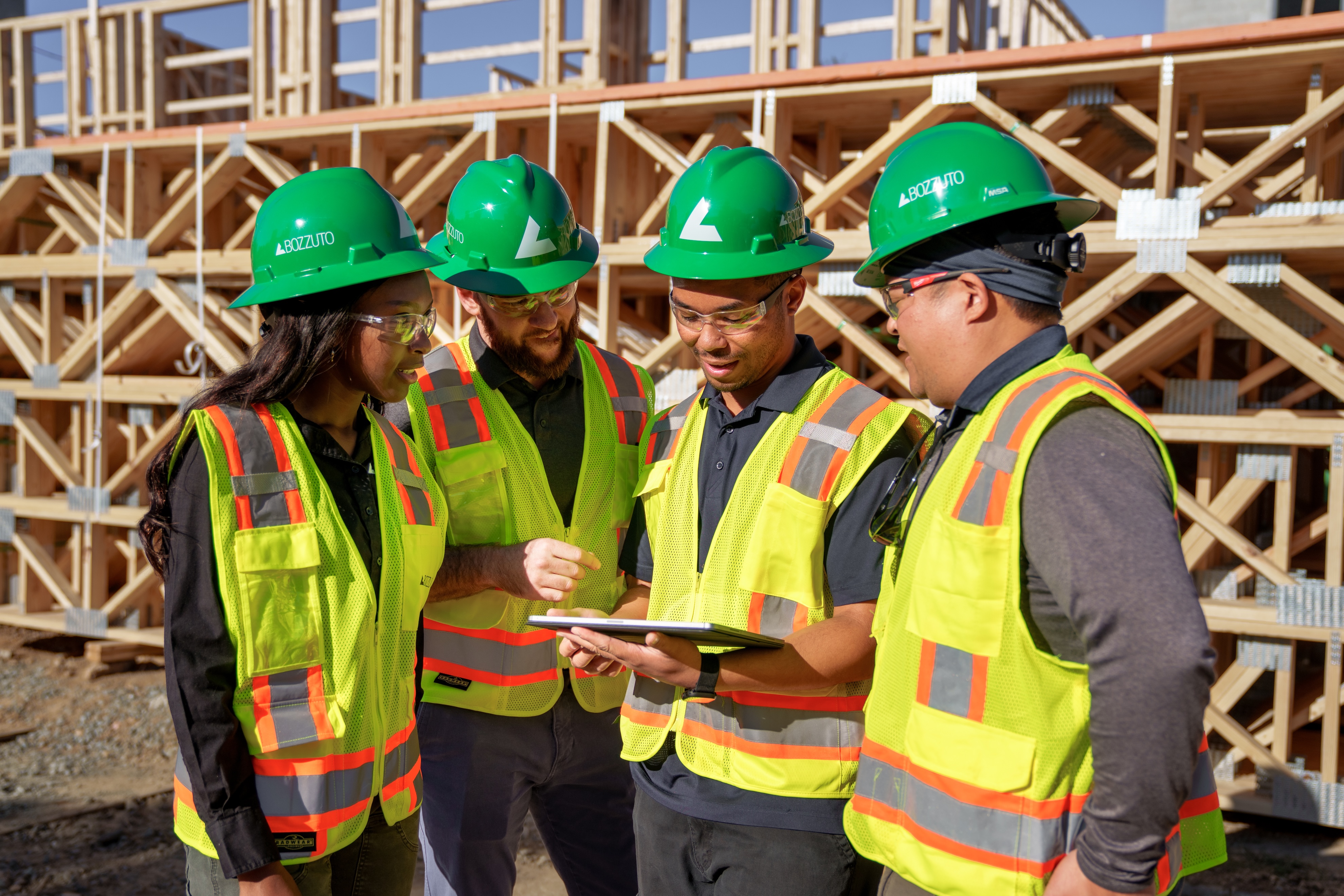 Four construction workers in safety gear discussing plans.